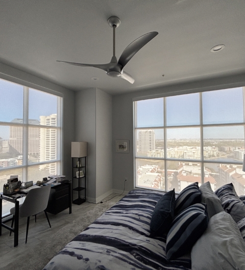 Custom motorized shades installed on large floor-to-ceiling high-rise windows in a modern bedroom in Las Colinas TX.