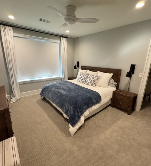 Custom motorized roller shades installed in a modern Granbury TX bedroom with solid wood furniture.