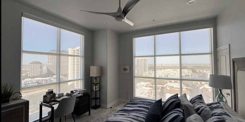 Custom motorized shades installed on large floor-to-ceiling high-rise windows in a modern bedroom in Las Colinas TX.